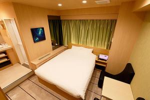 Un pequeño dormitorio con una cama blanca y una ventana en Think・Hotel・Think, en Ebina