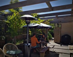 two people sitting at a table under an umbrella at Torquay Homestay Guesthouse in Torquay