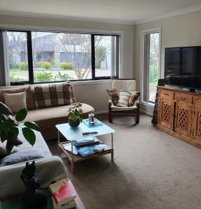 Torquay Homestay Guesthouse في توركوي: غرفة معيشة مع أريكة وتلفزيون