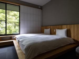 a bedroom with a large bed and a large window at 別府ホテル塒 Beppu Hotel Negura in Beppu