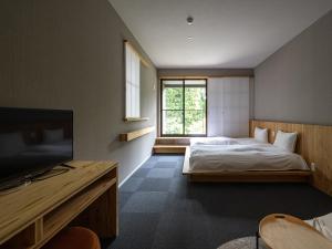 別府市にある別府ホテル塒 Beppu Hotel Neguraのベッドルーム(ベッド1台、テレビ付)