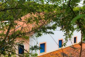 a white building with blue windows and trees at Casarão dos Uchoa in Guaramiranga