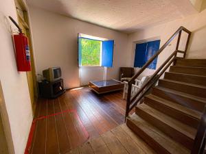 sala de estar con escalera y TV en Casarão dos Uchoa en Guaramiranga