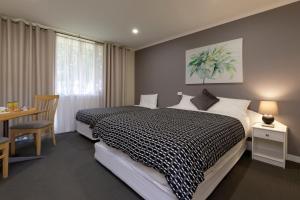 a bedroom with a black and white bed and a table at Keilor Motor Inn in Keilor