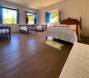 a bedroom with a bed and wooden floors and windows at Casarão dos Uchoa in Guaramiranga