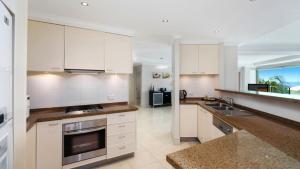 a kitchen with white cabinets and a counter top at Unit 13 - 3 Bedroom Ocean View in Terrigal +3 photos