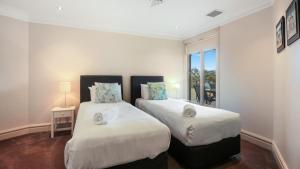two beds in a room with a window at Unit 13 - 3 Bedroom Ocean View in Terrigal