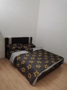 uma cama com um cobertor preto com estrelas douradas em Mahren Homestay - Homestay Merlimau Serkam Melaka 