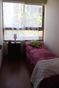 une petite chambre avec un lit et une fenêtre dans l'établissement Aparthotel Santiago Capital, à Santiago