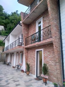a brick building with a balcony and tables and chairs at Family house in Borjomi