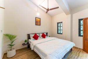 1 dormitorio con 1 cama grande con almohadas rojas en Villa Barbosa, 2 BHK Villa & Luxury Rooms near Colva, Sernabatim, Benaulim Beach en Colva