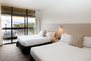a hotel room with two beds and a balcony at The Terrace Hotel Adelaide in Adelaide