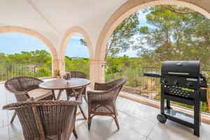 a patio with a table and chairs and a grill at Villa Rosa in Cala Santanyi