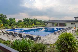 a swimming pool with chairs and a house at Soaltee Westend Resort Chitwan in Chitwan