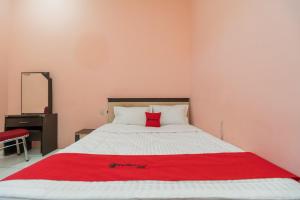 a bedroom with a bed with a red blanket on it at RedDoorz near Silangit International Airport in Siborongborong