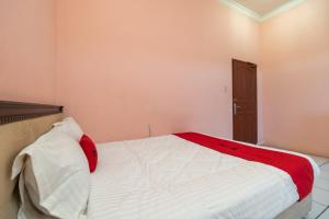 RedDoorz near Silangit International Airport في Siborongborong: غرفة نوم بسرير ابيض كبير مع بطانيه حمراء