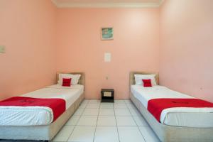 two beds in a room with pink walls at RedDoorz near Silangit International Airport in Siborongborong