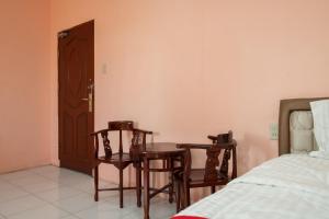 a room with two chairs and a table and a bed at RedDoorz near Silangit International Airport in Siborongborong