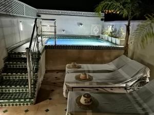 a swimming pool with two beds in a room at Riad Dalla Santa in Marrakesh