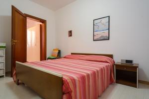 a bedroom with a bed with a striped blanket at Villa Rita a 200m dal mare in I Bacini