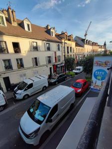 Ein weißer Lieferwagen parkt auf einer Stadtstraße mit Autos in der Unterkunft Studio cosy proche Paris, Stade de France in Pierrefitte-sur-Seine