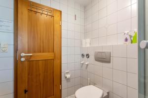 a bathroom with a toilet and a wooden door at Ferienwohnung Chiemgau - erleben in Siegsdorf
