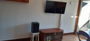 sala de estar con TV en la pared y mesa en Studio aux pieds des pistes Roche Béranger, en Chamrousse