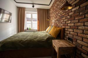 sypialnia z ceglaną ścianą, łóżkiem i stołem w obiekcie Apartament Hansa Klossa w Olsztynie