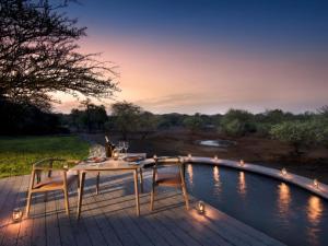 stół i krzesła na tarasie przy basenie w obiekcie Mbazo Safaris w mieście Pilanesberg