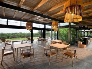 un patio con mesas, sillas y lámparas de araña en Mbazo Safaris, en Pilanesberg