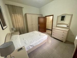 a bedroom with a bed and a dresser and a mirror at Seafront Apartment with Balcony Overlooking Marina in Għajnsielem