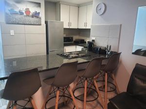 a kitchen with a counter with four chairs around it at DURBAN BEACHFRONT Tenbury 903 in Durban