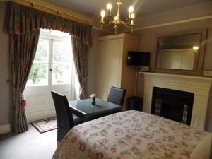 a bedroom with a table and a fireplace and a window at Ryvington Apartments in Abergavenny