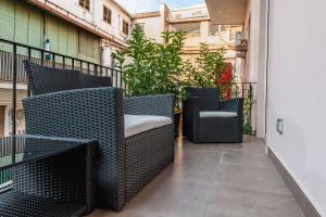 uma varanda com cadeiras e plantas num edifício em Ferrini Home - Riso 80 em Catânia