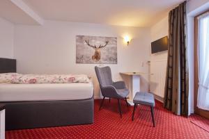 ein Hotelzimmer mit einem Bett und zwei Stühlen in der Unterkunft Alpen Gästehaus in Bad Kohlgrub