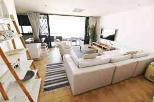 a living room with a white couch and a tv at 30 Degrees Beach Apartment Umdloti in Umdloti