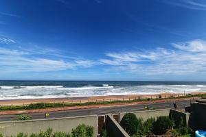 a road next to a beach with the ocean at 30 Degrees Beach Apartment Umdloti in Umdloti