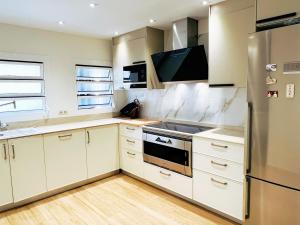 uma cozinha com armários brancos e um frigorífico de aço inoxidável em Cheerful Townhouse Center Sitges 5 bedrooms Pool and Terrace em Sitges