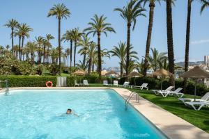 a person swimming in a pool with palm trees in the background at Parador de Jávea in Jávea