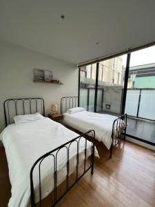 two beds in a room with a large window at Beachside Sunshine Lifestyle-great price-entire aprt at Port Melbourne in Melbourne