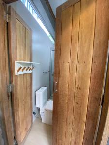 a bathroom with wooden doors and a toilet at Forest Guesthouse in Ban Don Muang
