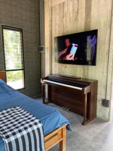 1 dormitorio con piano y TV de pantalla plana en Forest Guesthouse, en Ban Don Muang