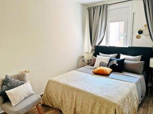 um quarto com uma cama com almofadas e uma cadeira em Cheerful Townhouse Center Sitges 5 bedrooms Pool and Terrace em Sitges