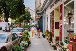 twee mensen lopen over een stoep met een fiets bij grätzlhotel Serviten in Wenen