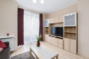 a living room with a couch and a tv at Czarnieckiego Apartment with Balcony Poznań by Renters in Poznań