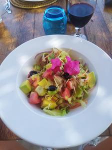 a white bowl of salad with a glass of wine at Mtende Beach Bungalow océan view in Mtende