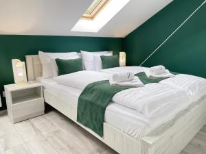 1 dormitorio con 1 cama blanca grande y paredes verdes en Csatári Ház - Szekszárd, en Szekszárd