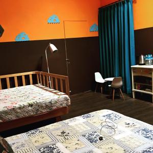 1 dormitorio con 2 camas, mesa y lámpara en 麵包樹舍 Breadfruit B&B, en Guangfu