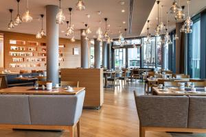 a restaurant with wooden tables and chairs and chandeliers at Thermenhotel Gesundheits-Bad Buchau in Bad Buchau