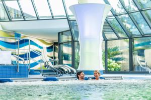 zwei Personen schwimmen in einem Pool in einem Wasserpark in der Unterkunft Thermenhotel Gesundheits-Bad Buchau in Bad Buchau